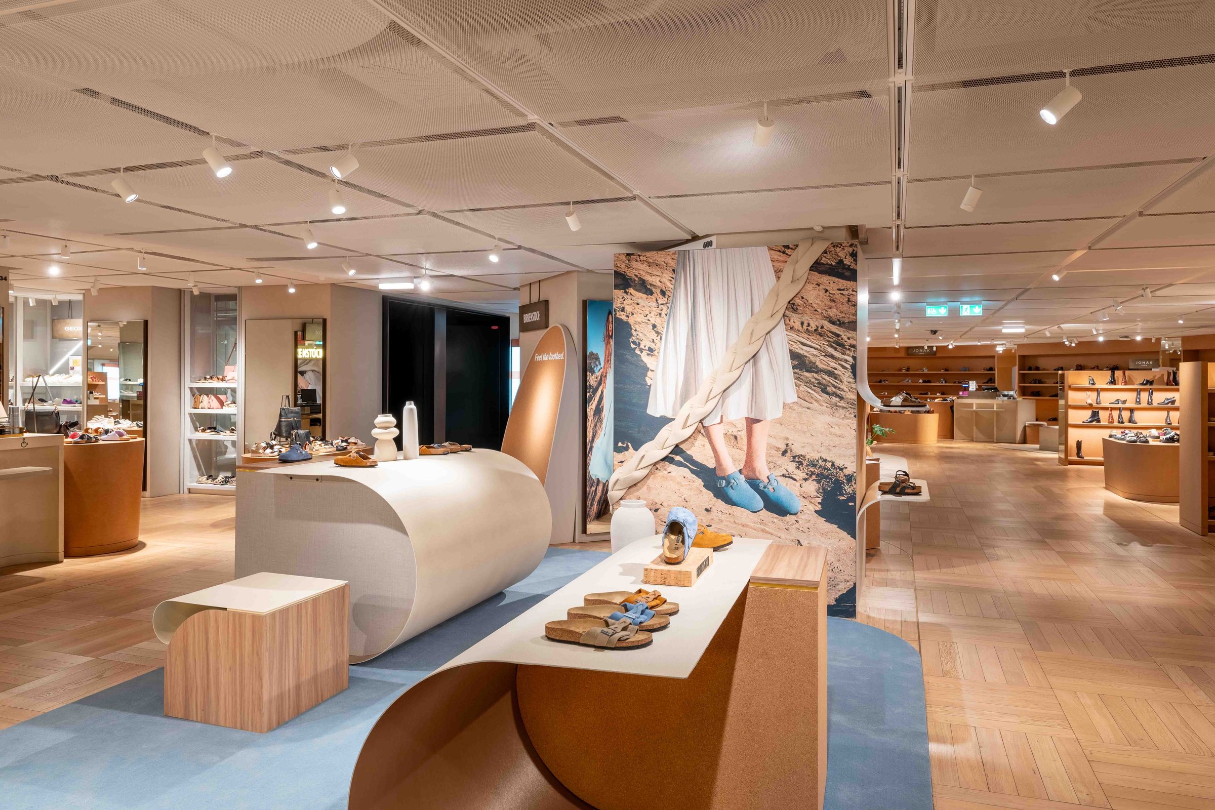 Birkenstock corner at Galeries Lafayette Haussmann, curved seating on a blue rug